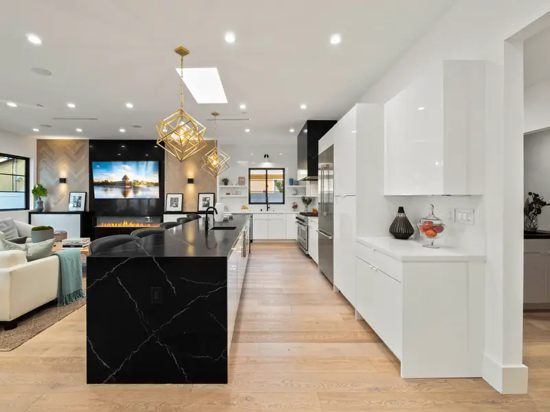 Kitchen countertops in Los Angeles, CA: black waterfall island with white veining in a bright open kitchen