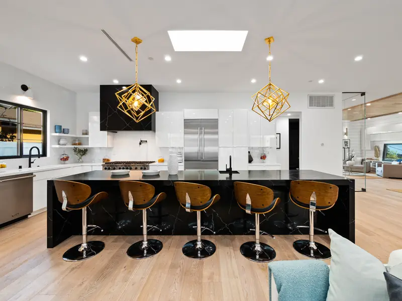 Kitchen countertops in Los Angeles, CA: black island countertop with seating under brass pendant lights