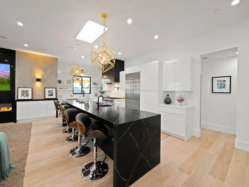 Kitchen countertops in Los Angeles, CA: dark waterfall island with white veining in a white kitchen