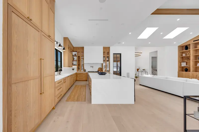 Kitchen countertops in Porter Ranch, CA: long kitchen with white countertops and a waterfall island between oak cabinets