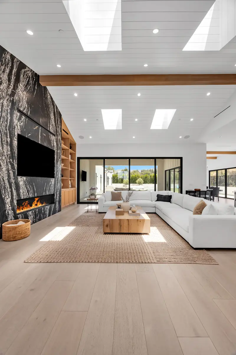 Slab fireplace in Porter Ranch, CA: dark veined slab fireplace wall with a linear fire beside a white sectional in a skylit living room
