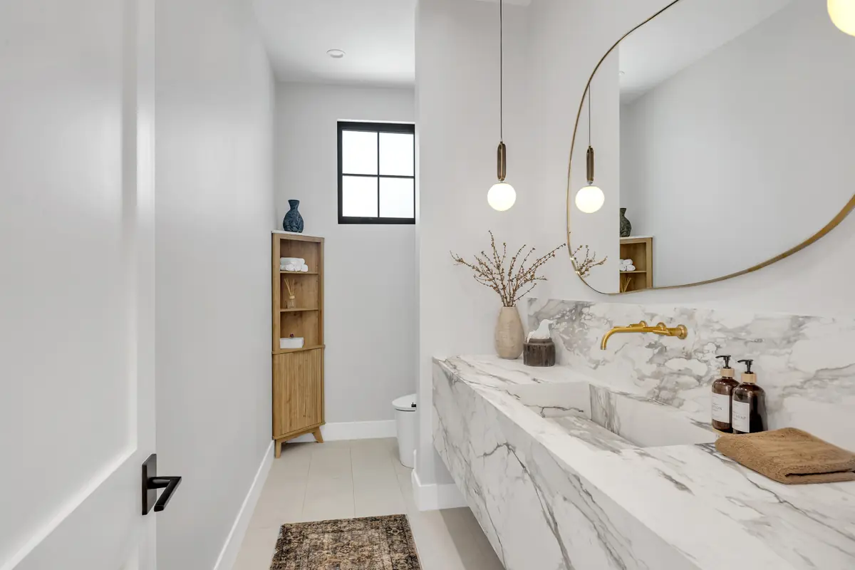 Vanity countertop in Porter Ranch, CA: powder room with a veined white floating vanity top and round mirror