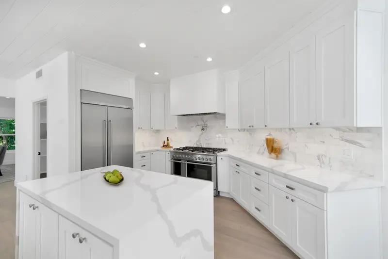 Kitchen countertops in Sherman Oaks, CA: waterfall island with a veined white countertop and stainless appliances