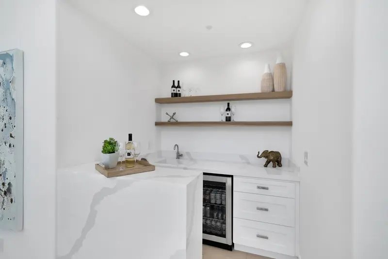 Kitchen countertops in Sherman Oaks, CA: bar counter with a veined white waterfall edge and floating shelves