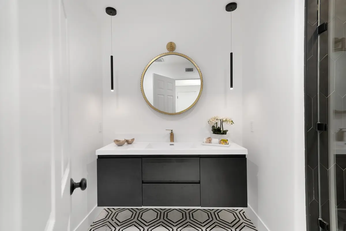 Vanity countertop in Sherman Oaks, CA: floating black vanity with a white countertop and round brass mirror