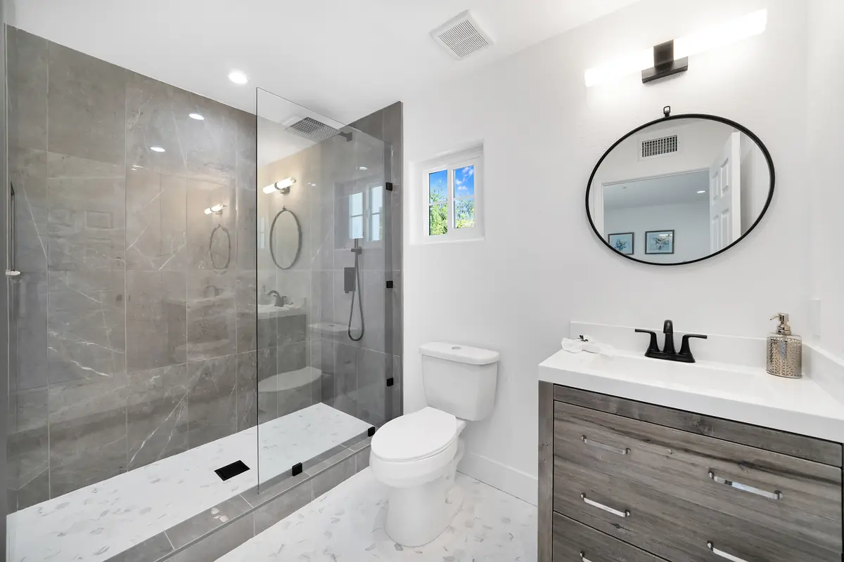 Vanity countertop in Sherman Oaks, CA: gray vanity with a white countertop beside a stone-walled shower