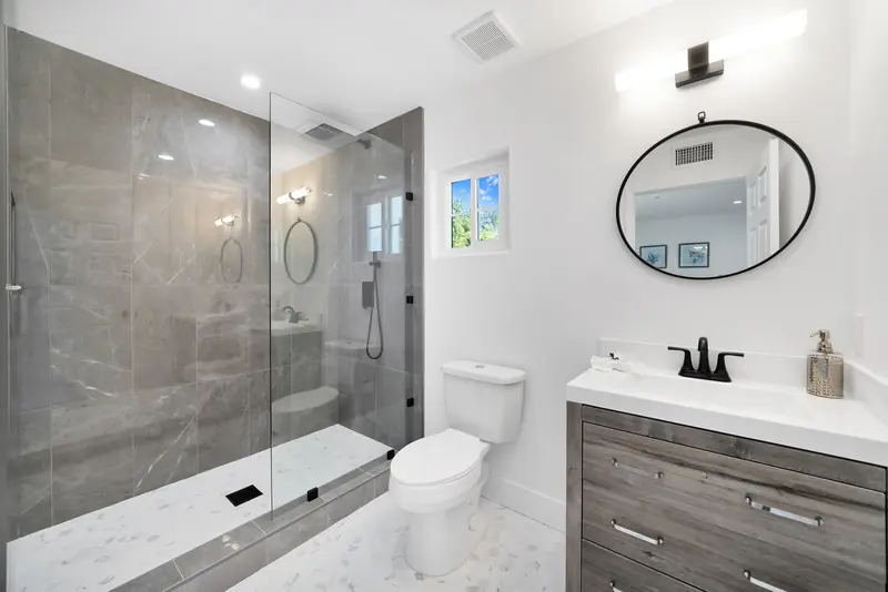 Vanity countertop in Sherman Oaks, CA: gray vanity with a white countertop beside a stone-walled shower